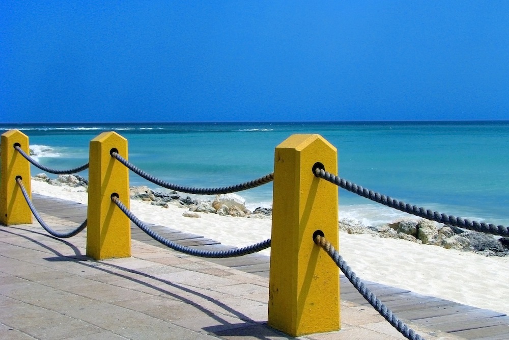 blue ocean, boardwalk, yellow pylons, rope railing